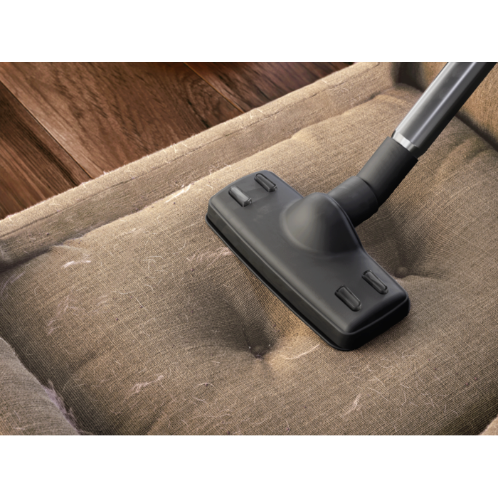 Upholstery nozzle vacuuming pet hair from dog bed or other upholstery