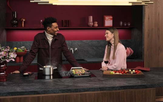 Man and woman standing in a kitchen while cooking.