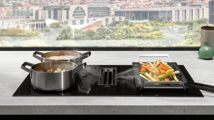 Inductiekookplaat met afzuigkap in een keuken met uitzicht op de stad