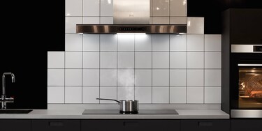 Zalm koken op een inductiekookplaat, terwijl de overtollige stoom wordt afgezogen door de afzuigkap