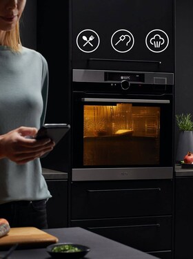 Vrouw die haar telefoon vasthoudt in een keuken
