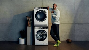 Man die naast een wasmachine staat