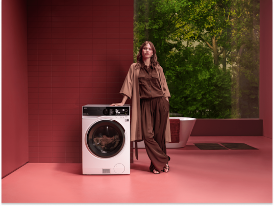 Vrouw die naast een AEG wasmachine staat.