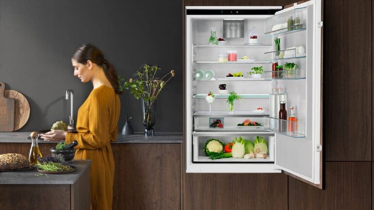 Vrouw staat in een keuken met een koelkastdeur open