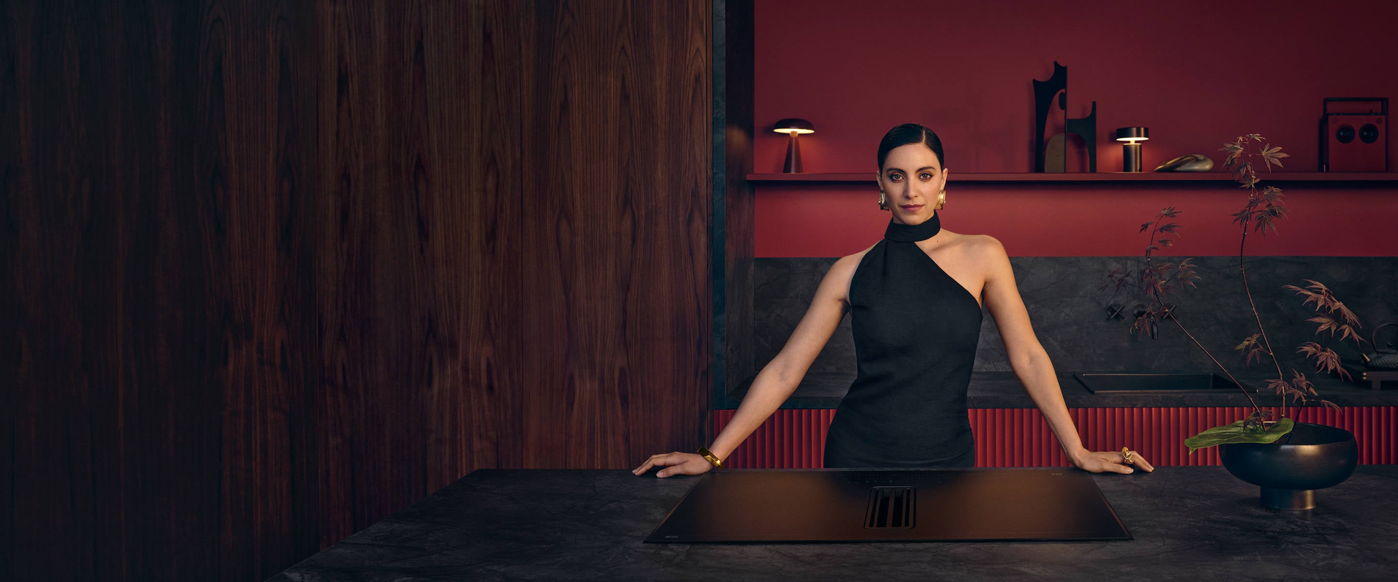 Vrouw die in de keuken staat bij een AEG SaphirMatt® kookplaat met afzuiging