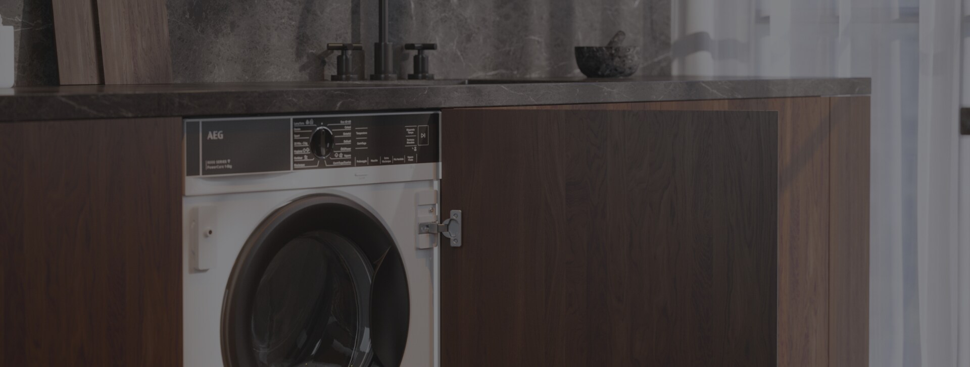 Een keukenblad met een ingebouwde AEG 8 kg wasmachine met een deur van een kast die open staat.