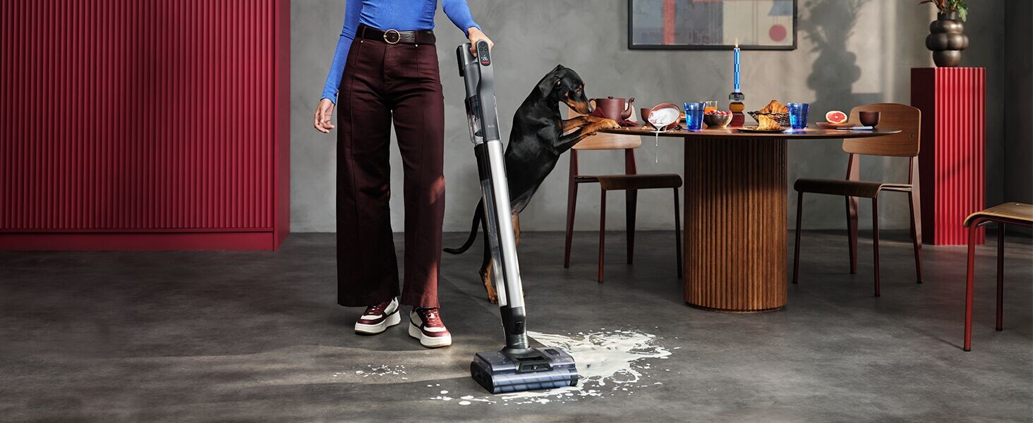 Vrouw die aan het stofzuigen en dweilen is in een woonkamer met een Wet & Dry steelstofzuiger van AEG.