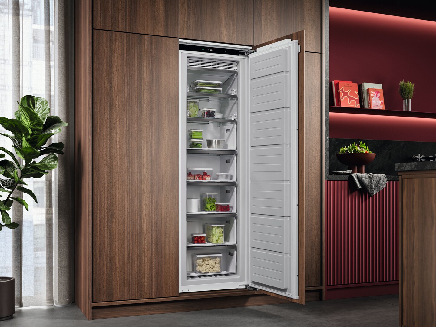 Een keuken met bordeaux rode kasten en een ingebouwde AEG vriezer met 7 lades die open staat en gevuld is met voedsel.
