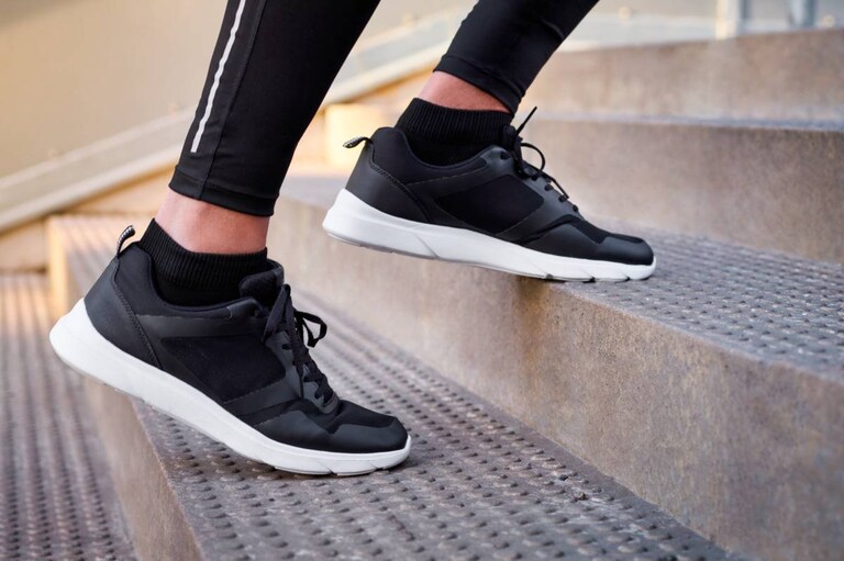 Schoenen en benen in beeld van iemand die een trap op loopt.